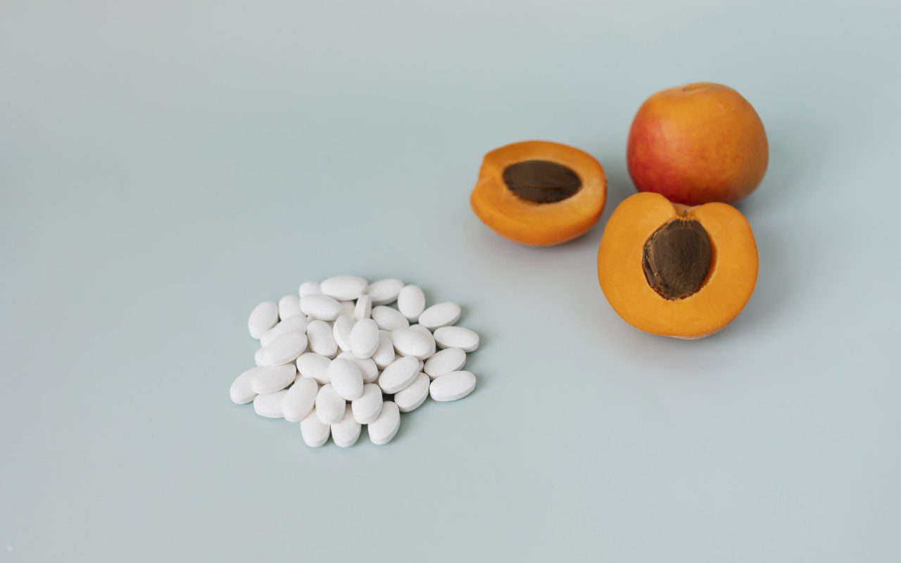 Apricots and white pills on blue background.